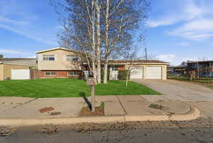 Tri-level home featuring brick siding, a garage, and concrete driveway
