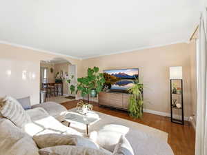 Living area with wood finished floors, arched walkways, and ornamental molding