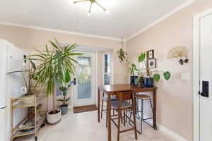 Dining space with crown molding and baseboards