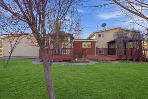 Rear view of property featuring brick siding, a deck, and a lawn