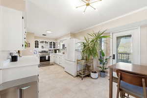 Kitchen featuring light countertops, white fridge with ice dispenser, electric range, white cabinets, and glass fronted cabinets