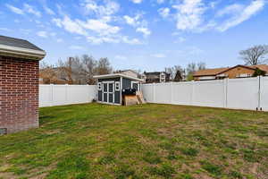Fenced backyard featuring a shed and a residential view