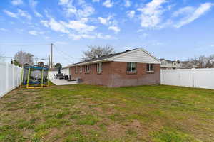 Back of house featuring a fenced backyard, a patio, and brick siding