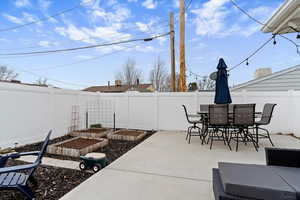 Fenced backyard featuring a vegetable garden, a patio, and outdoor dining space
