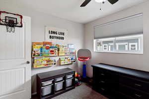 Playroom with dark colored carpet and a ceiling fan