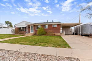 View of front facade with a carport, driveway, and brick siding
