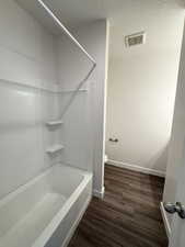 Full bathroom featuring dark wood-style flooring, a textured ceiling, and shower / bathtub combination