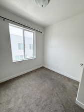 Unfurnished room with dark carpet and a textured ceiling