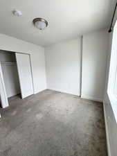 Unfurnished bedroom featuring a closet, carpet, and a textured ceiling