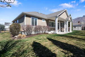 Back of property with a patio, a storage unit, and a shingled roof