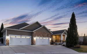 Craftsman-style house featuring a garage, stone siding, concrete driveway, and a porch