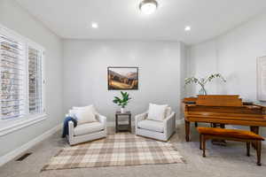 Sitting room with light colored carpet and recessed lighting