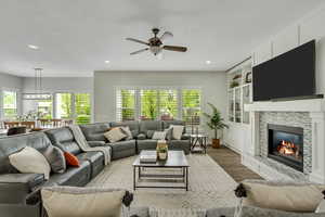 Living area with wood finished floors, a fireplace, a ceiling fan, recessed lighting, and built in shelves