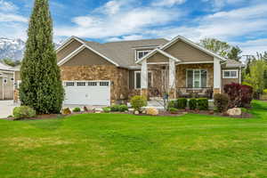 Craftsman house with stone siding, covered porch, and a garage