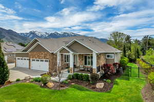 Craftsman inspired home with stone siding, driveway, a garage, a mountain view, and a porch