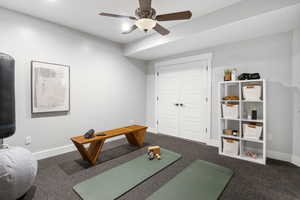 Exercise area with a ceiling fan and dark carpet