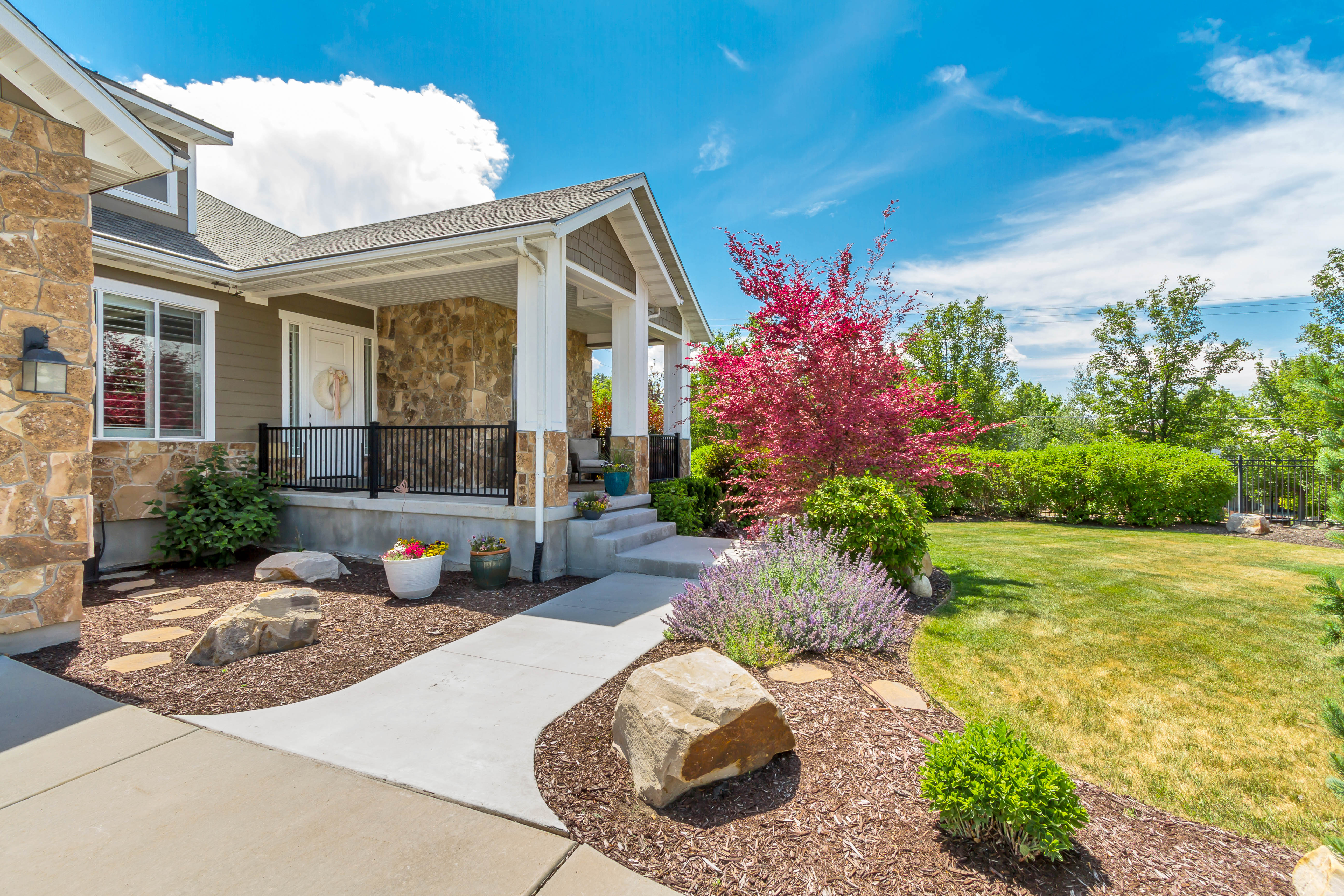 Stone facade with a covered front porch featuring white columns and black railings