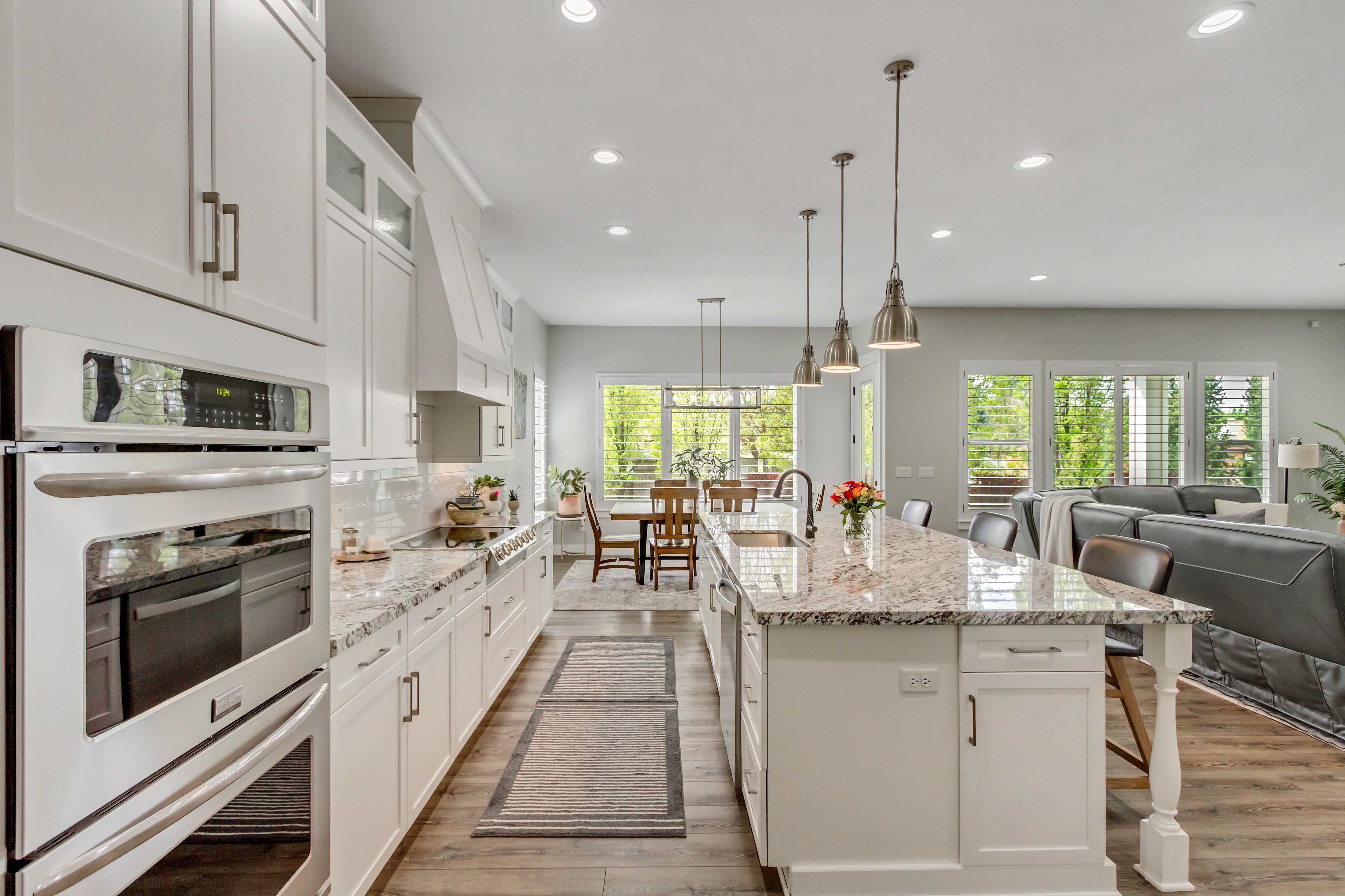 Kitchen featuring white cabinetry, a breakfast bar area, stainless steel appliances, light stone countertops, and open floor plan