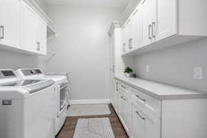 Laundry area featuring cabinet space, dark wood-style floors, and independent washer and dryer