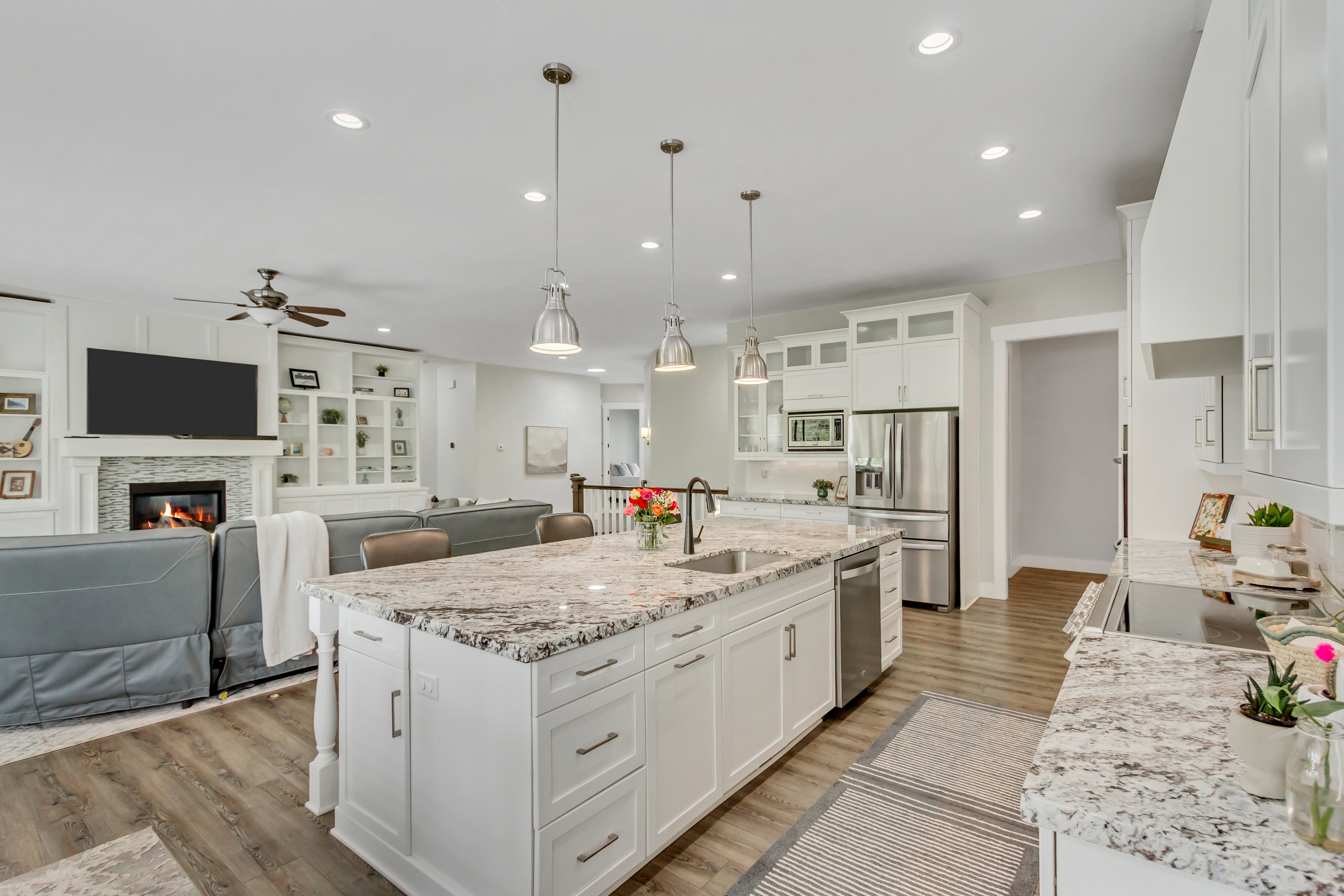 Kitchen featuring open floor plan, white cabinetry, light stone counters, and stainless steel appliances