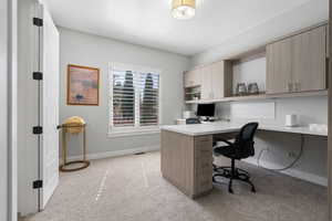 Office space featuring light colored carpet and built in study area