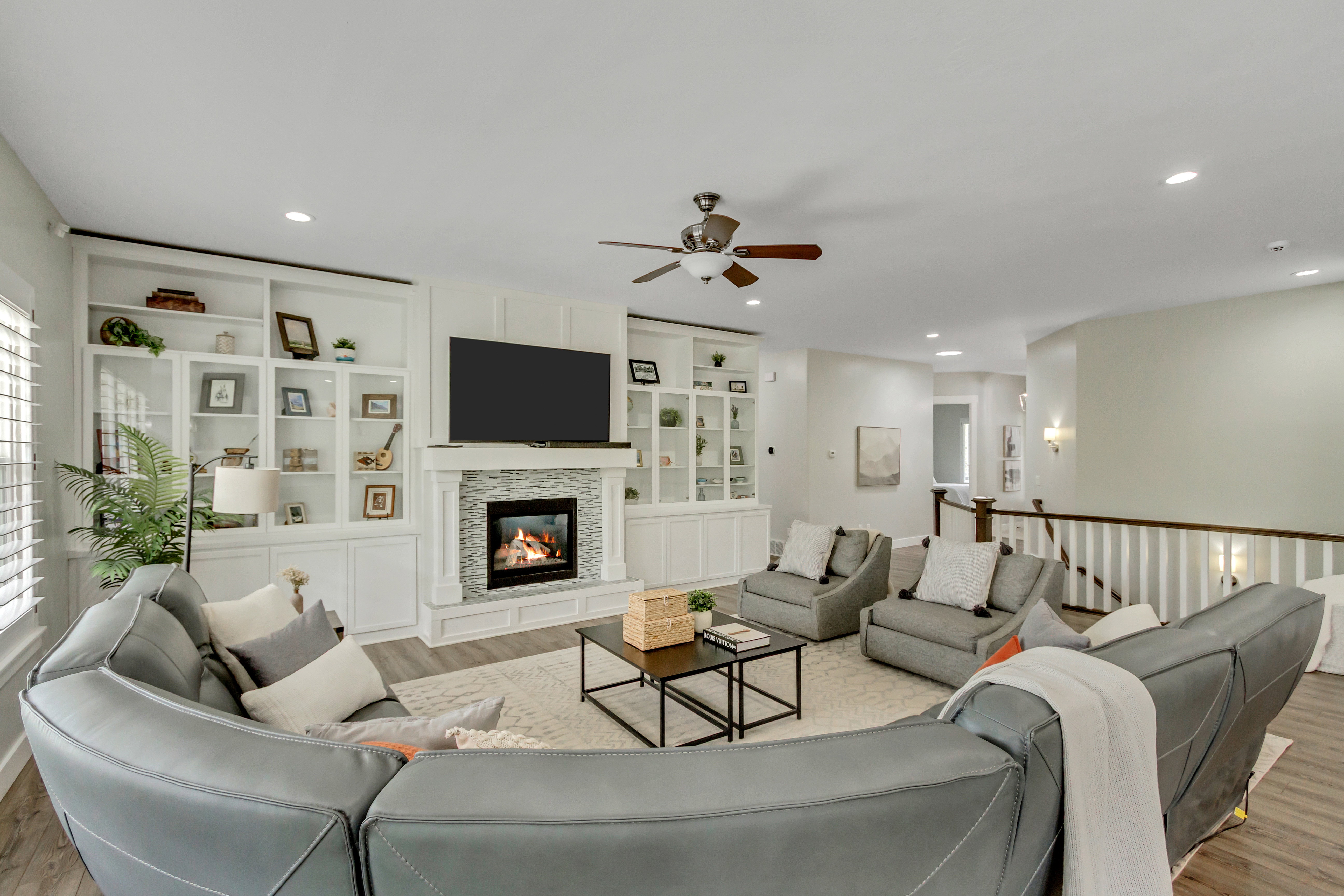 Living area featuring light wood-type flooring, a fireplace, ceiling fan, built in shelves, and recessed lighting