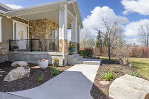 Doorway to property with stone siding and a porch