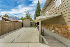 View of side of home featuring stone siding and a storage unit