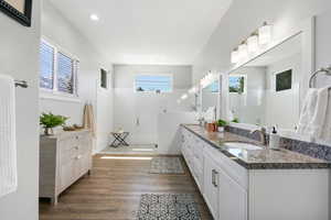 Bathroom featuring double vanity, plenty of natural light, a shower stall, dark wood-style floors, and recessed lighting