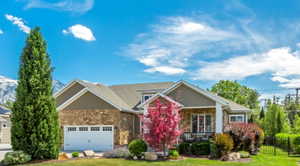 Stone and siding exterior with a pitched roofline, attached garage, and a covered porch