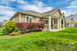 Back of property featuring a patio area, a shingled roof, a storage unit, and a mountain view