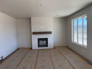Unfurnished living room with a glass covered fireplace and a textured ceiling