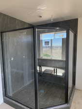 Bathroom with a marble finish shower, a textured ceiling, and light tile patterned floors