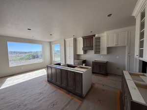 Two tone kitchen featuring a center island, two tone color scheme, a textured ceiling, and black electric stovetop