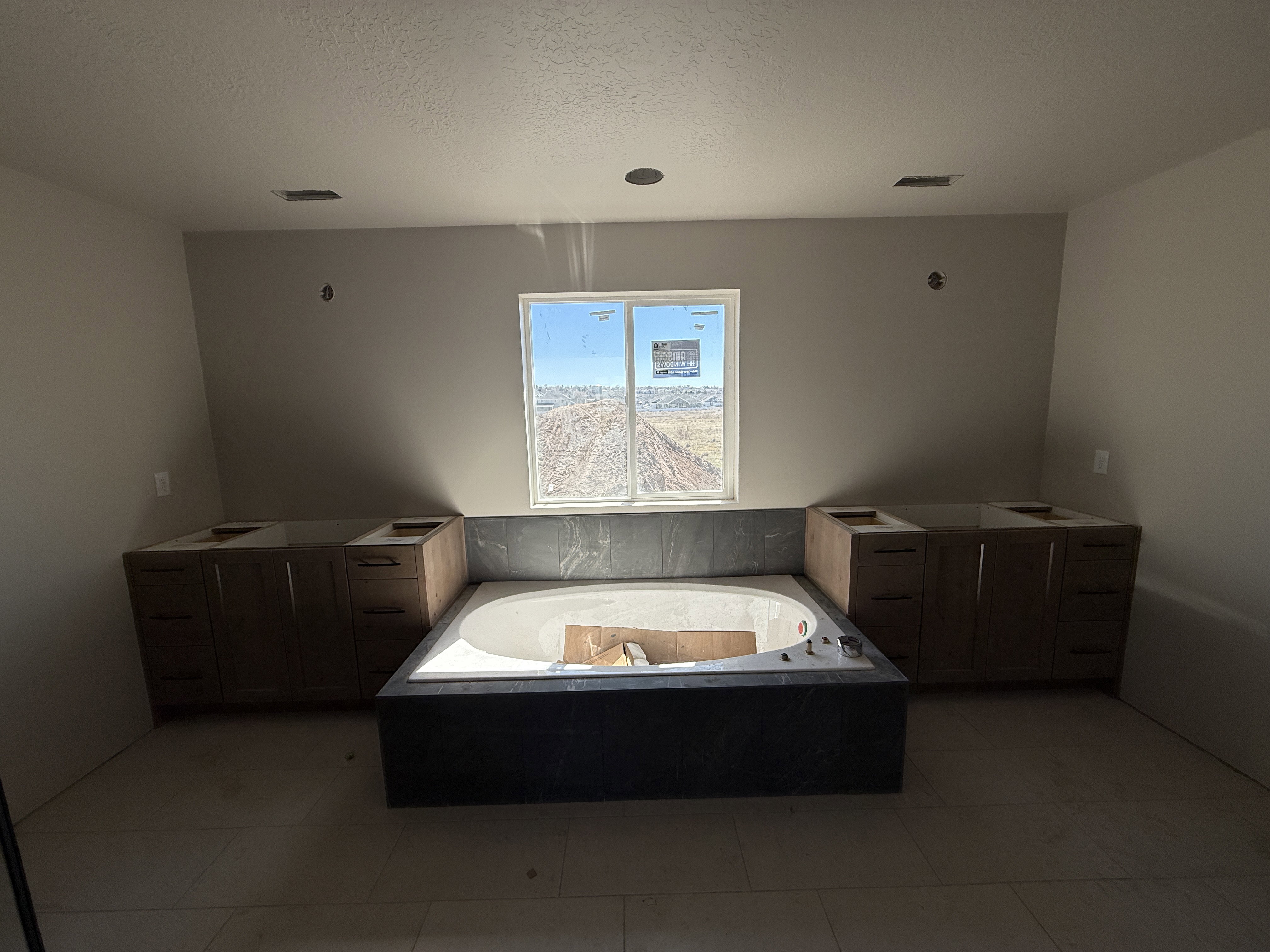Bathroom with a garden tub, vanity, a textured ceiling, and light tile patterned floors