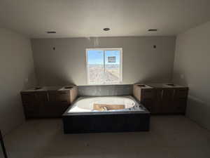 Bathroom with a garden tub, vanity, a textured ceiling, and light tile patterned floors