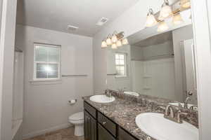 Bathroom with double vanity, a textured ceiling, and shower / bath combination