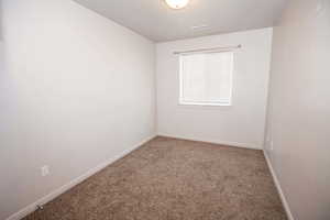 Spare room featuring carpet and baseboards