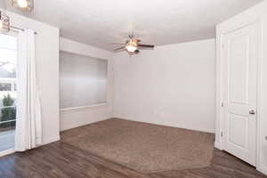 Unfurnished room featuring dark wood finished floors, ceiling fan, and a textured ceiling