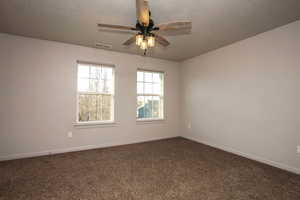 Primary Bedroom featuring a ceiling fan, dark colored carpet, and a textured ceiling