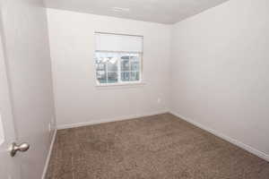 Empty room featuring dark carpet and a textured ceiling
