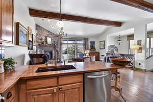 Kitchen featuring dishwasher, open floor plan, a fireplace, a peninsula, and dark wood finished floors