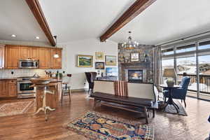 Living area with vaulted ceiling with beams, dark wood-style flooring, a fireplace, and hanging lights