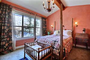 Bedroom with beamed ceiling, suspended lighting, and carpet flooring