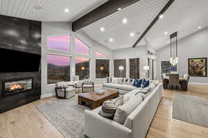 Living area featuring a large fireplace, a high wooden beamed ceiling, and light wood finished floors