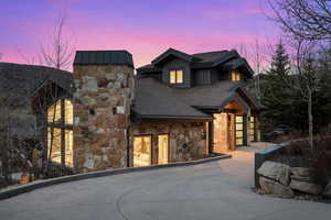 View of front of property with stone siding and roof with shingles
