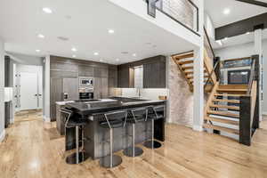 Kitchen featuring modern cabinets, light wood-style flooring, a breakfast bar, built in appliances, and recessed lighting