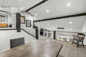 Unfurnished room featuring a warm lit fireplace, a wood ceiling with exposed beams, and recessed lighting