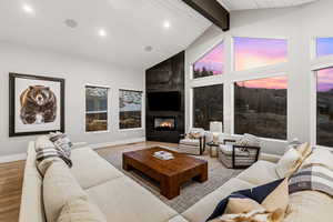 Living area with light wood finished floors, a fireplace, recessed lighting, and a high wooden beamed ceiling