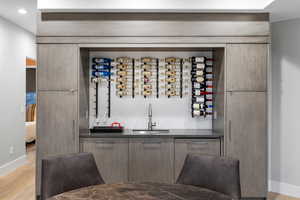 Bar area featuring dark countertops, modern cabinets, and light wood-style floors